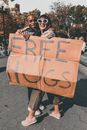 Man and Woman Holding Free Hugs Signage