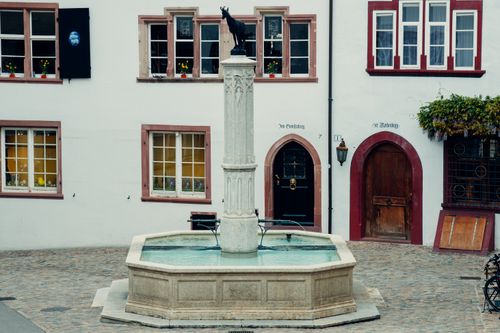 Free A picturesque fountain with a statue in Basel's historic square, surrounded by quaint architecture. Stock Photo