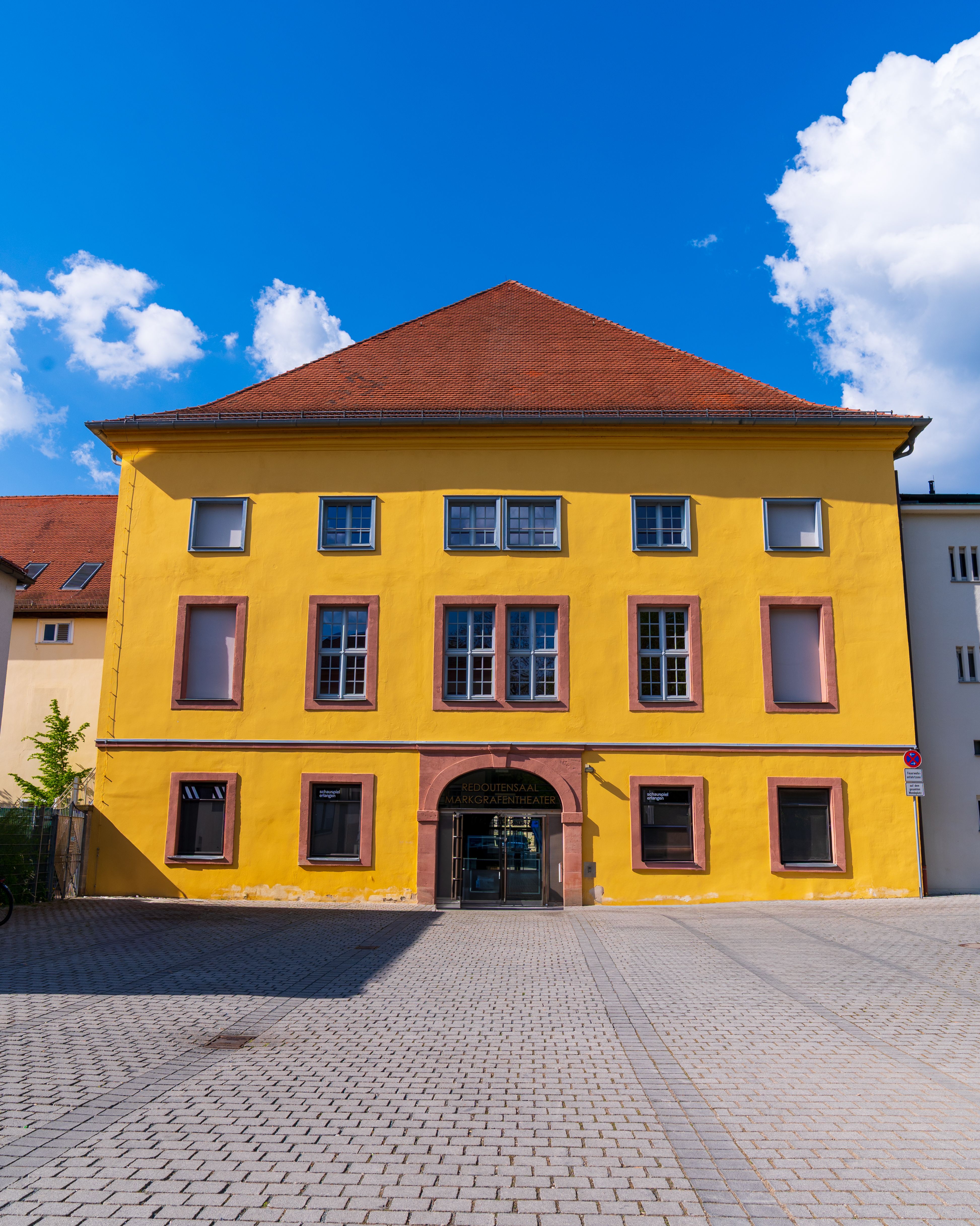 Bright yellow historic building with blue sky backdrop in urban setting.