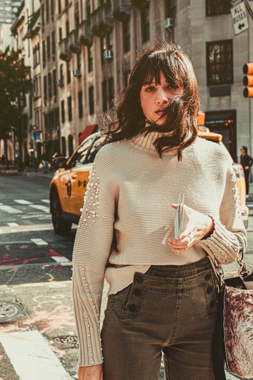 Woman Wearing Gray Turtleneck Sweater and Gray Jeans Posing on Street