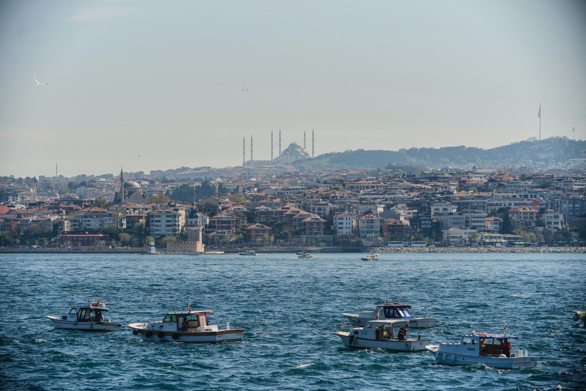 Istanbul cityscape with boats on Bosphorus, showcasing skyline and mosques in clear daylight.