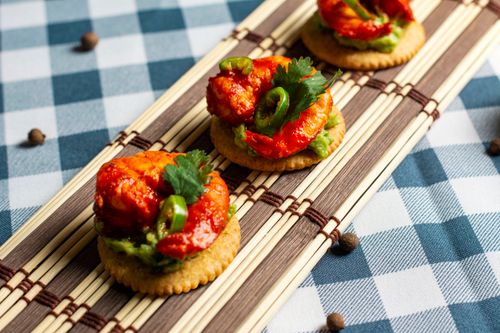 Free Tasty shrimp appetizers with guacamole and jalapeños served on crackers. Stock Photo