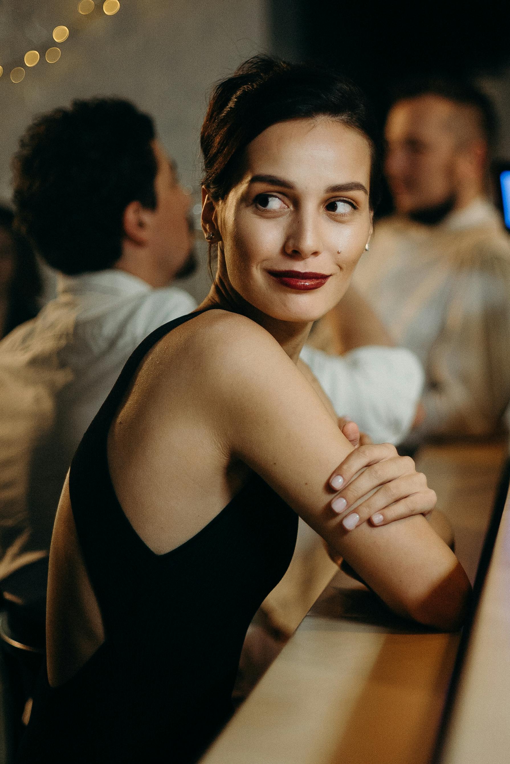 在别致的酒吧环境中，一位时尚女士微笑着转身，捕捉到温暖的夜晚氛围