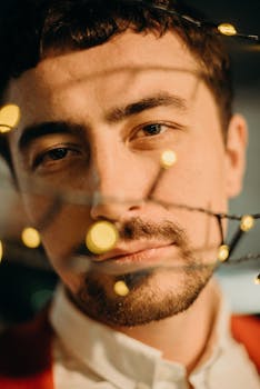 一个手持串灯的男人的特写肖像，在夜晚唤起了温暖而喜怒无常的氛围