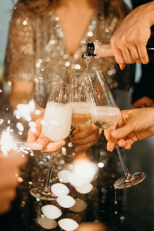Free Person Pouring Champagne on Champagne Flutes Stock Photo