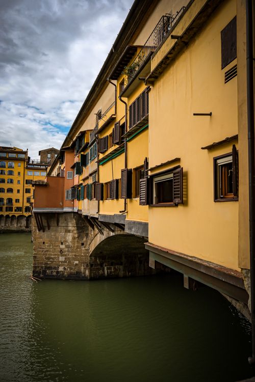 Free View of the famous Ponte Vecchio bridge in Florence with colorful buildings over the Arno River. Stock Photo