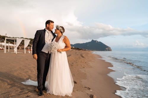 Newlywed couple embracing on tropical sandy seashore
