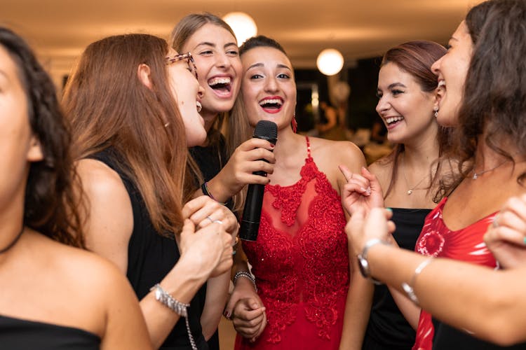 Elegant Ethnic Women With Microphone Congratulating Friend While Laughing