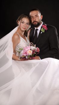 A beautiful wedding couple posing elegantly in a studio setting.