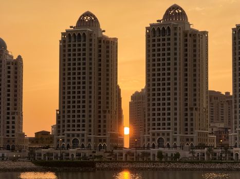 Scenic view of the Doha skyline with modern towers silhouetted against a golden sunset along the waterfront.