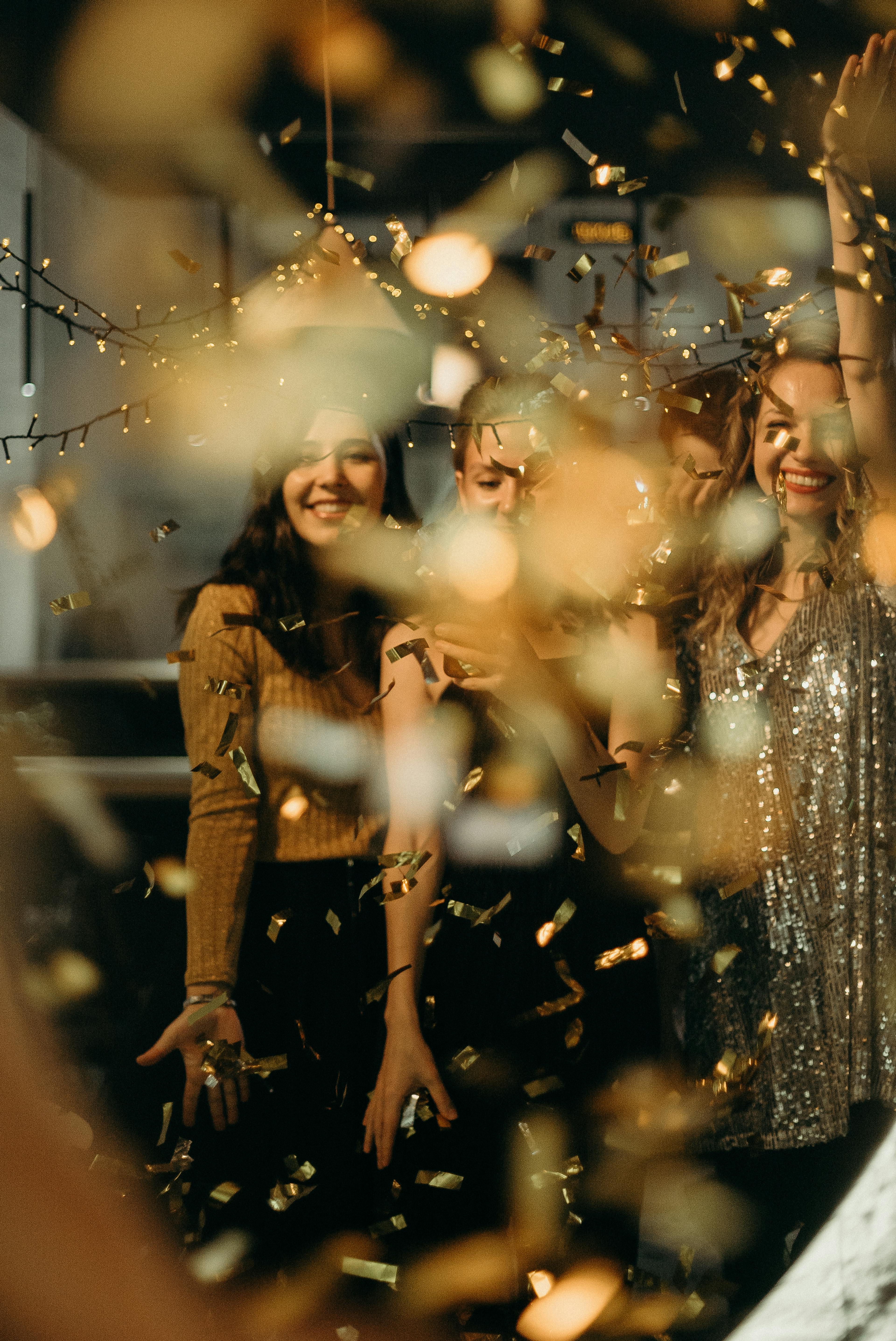 Selective Focus Photography of Smiling Women Standing Behind String Lights