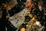 沉浸在节日庆祝中的男人，躺在金色五彩纸屑里，洋溢着幸福感