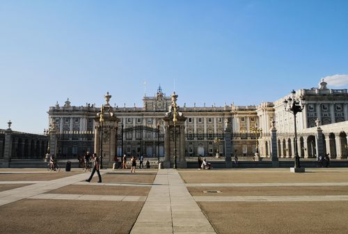 Free Stunning view of the Royal Palace of Madrid with people strolling under a clear blue sky. Stock Photo