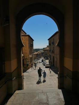 Archway framing a street scene in Toledo, Spain, showcasing historic architecture and vibrant life.