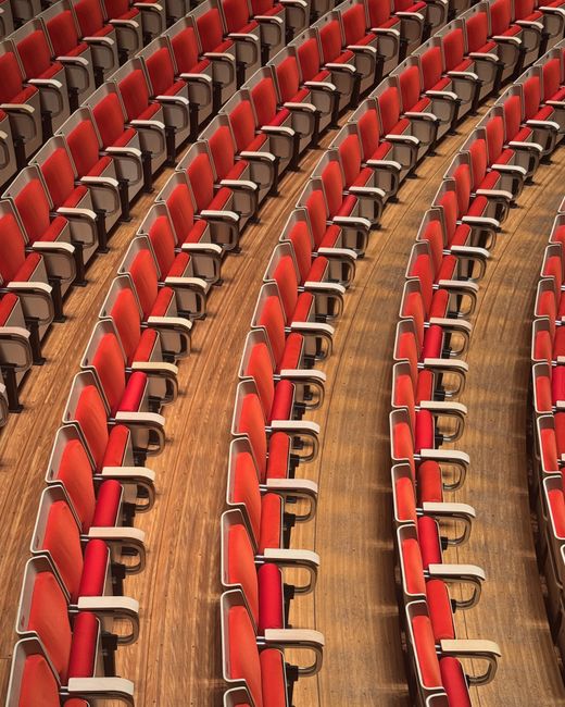 Abstract view of rows of red seating in the Sydney Opera House, showcasing geometric patterns and comfort.