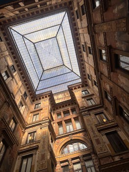 A breathtaking view of a Roman building's ornate interior illuminated by a glass ceiling.