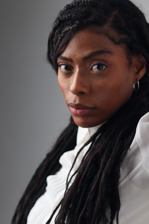 Free Focused portrait of a woman with braided hairstyle wearing a white top, conveying depth and elegance. Stock Photo