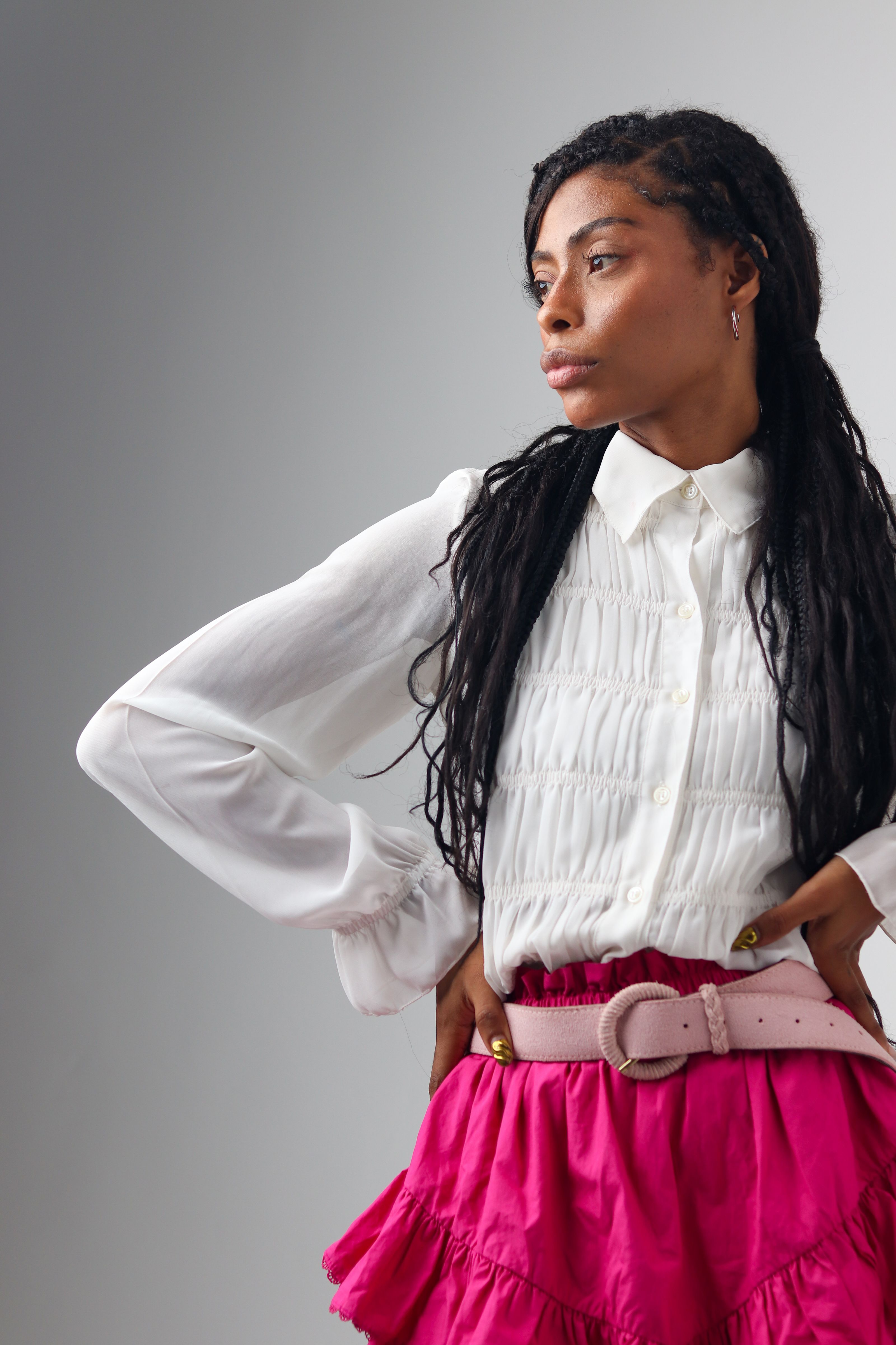 Retrato elegante de uma mulher de blusa branca e saia rosa. Visual moderno e estiloso.
