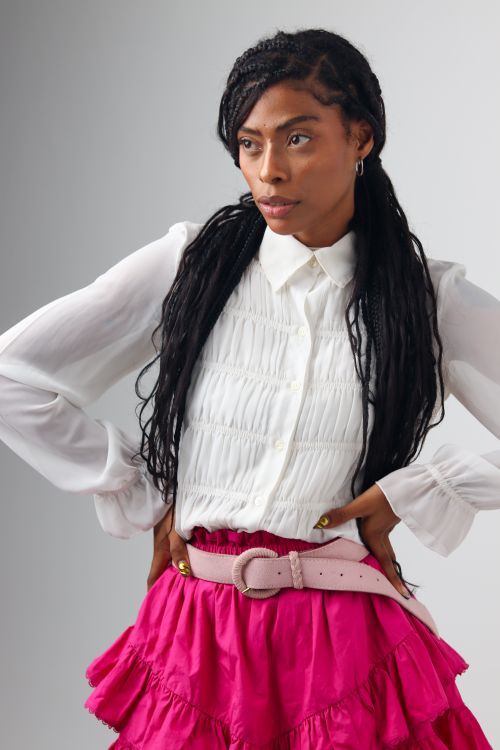 Free Fashionable woman posing confidently in a white blouse and pink ruffle skirt. Stock Photo