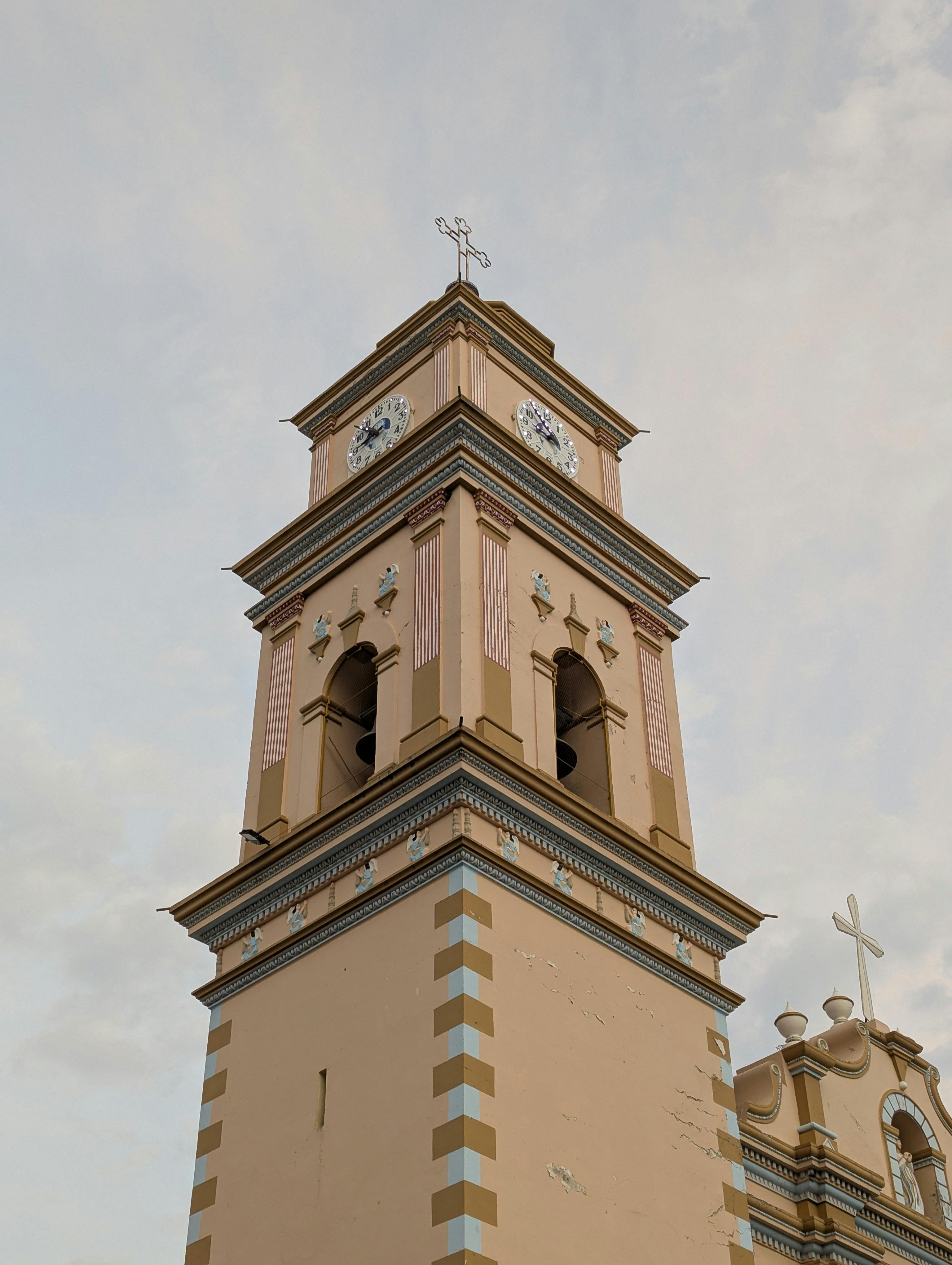 Close-up of a historic church bell tower featuring ornate architecture and a prominent clock under a clear sky.