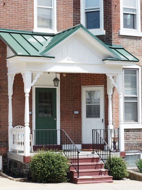 Elegant red brick porch with white trim and green roof in Perkasie, Pennsylvania.