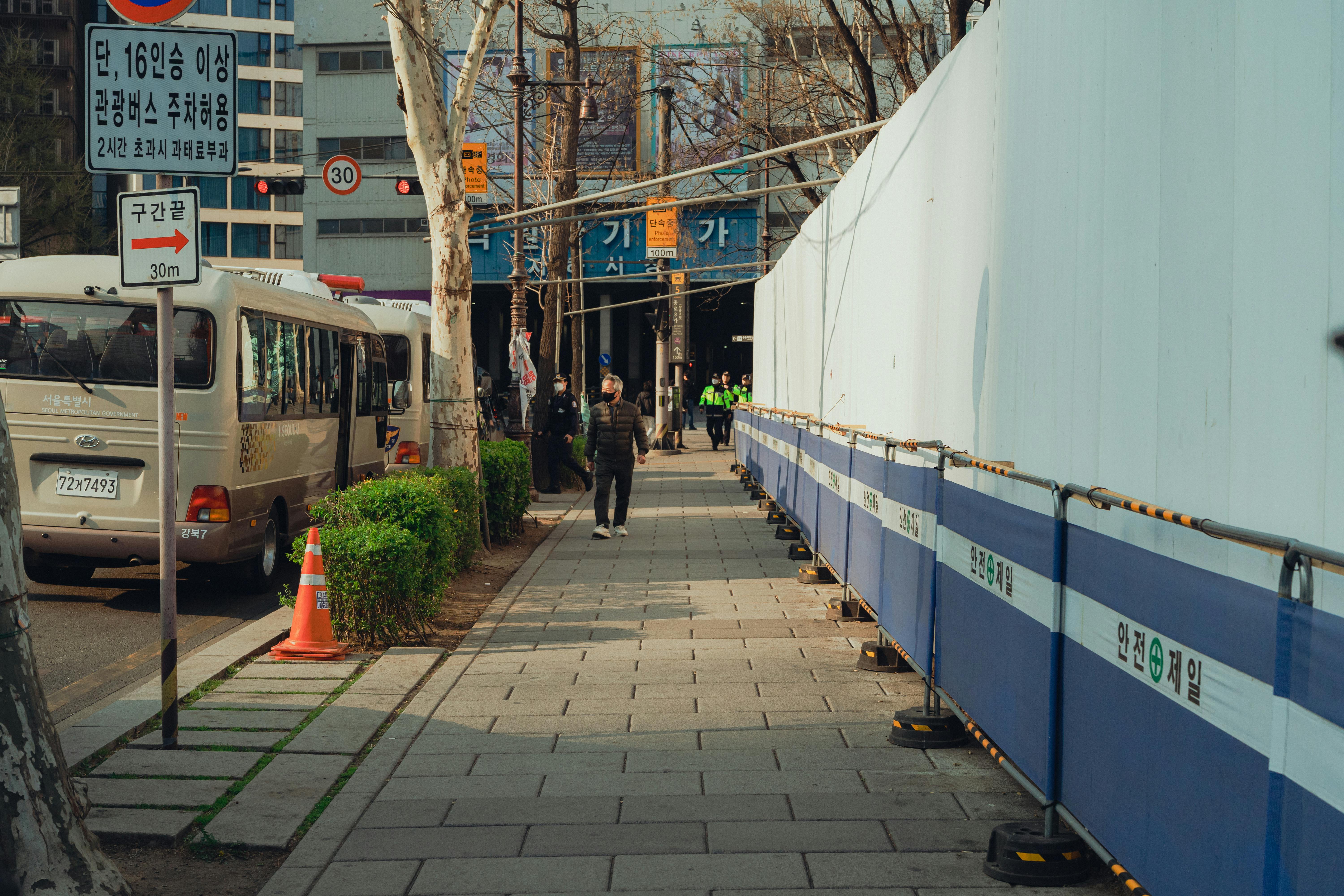 A street in Seoul, South Korea showing buses, pedestrians, and a construction site.