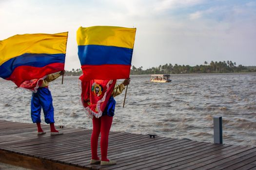 Vibrant Colombian flags displayed over a waterfront under a clear sky, showcasing cultural pride.