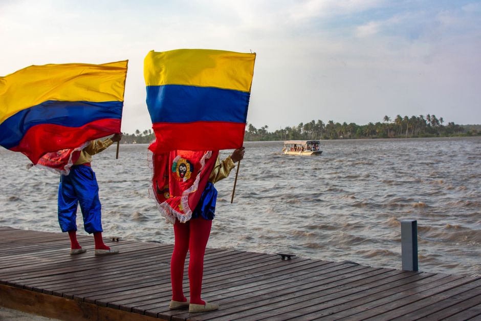 Vibrant Colombian flags displayed over a waterfront under a clear sky, showcasing cultural pride.