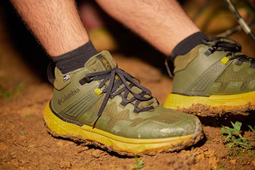Close-up of green hiking shoes on a muddy path, emphasizing adventure and outdoor activity.