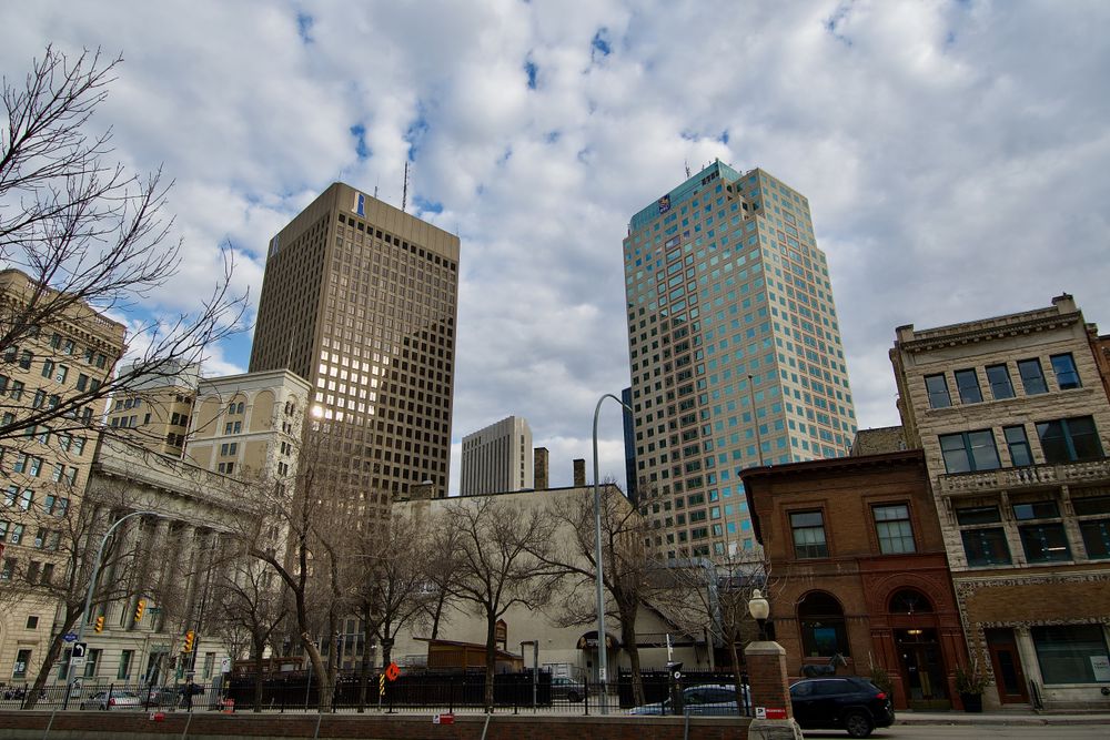 Scenic view of downtown Winnipeg, capturing modern and historical architecture beneath a cloudy sky.