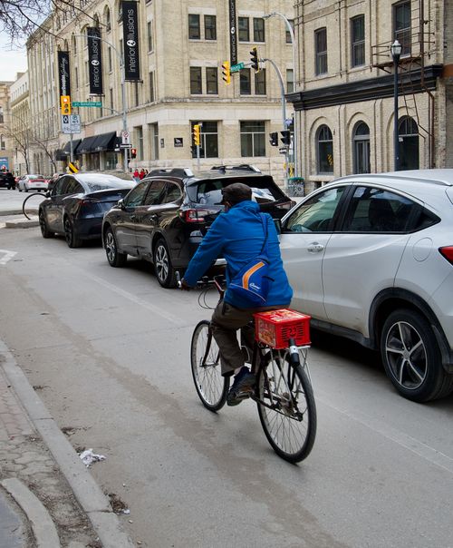 Free A cyclist rides through traffic in downtown Winnipeg on a cool day, showcasing urban commuting. Stock Photo