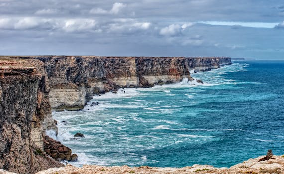 Breathtaking view of the Nullarbor cliffs meeting the ocean under a cloudy sky.