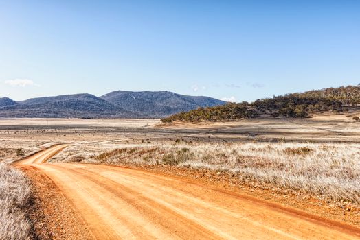 Discover the serene beauty of a winding country road under a clear blue sky with distant mountain views.