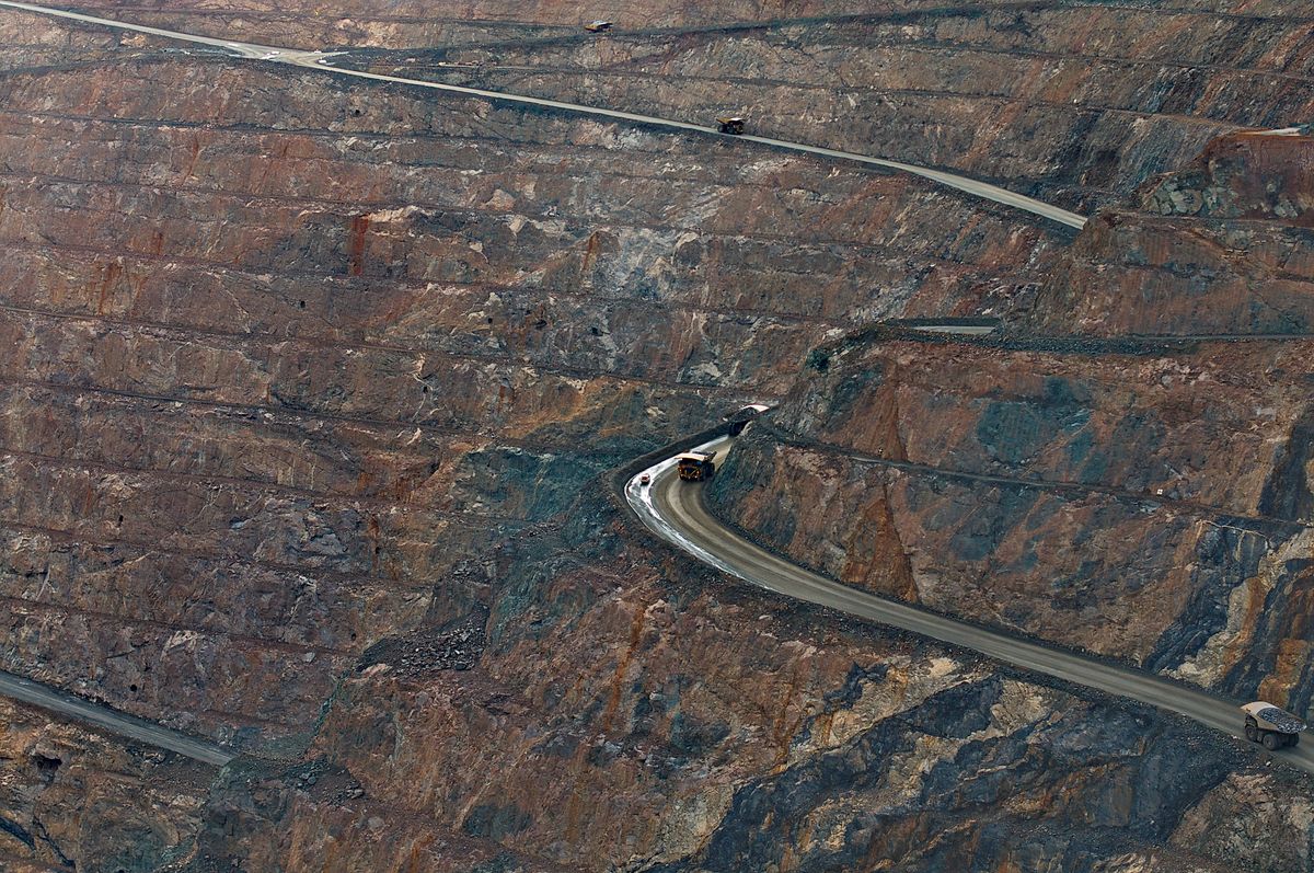Open-pit iron ore mine with haul trucks, representing Bellary's mining economy