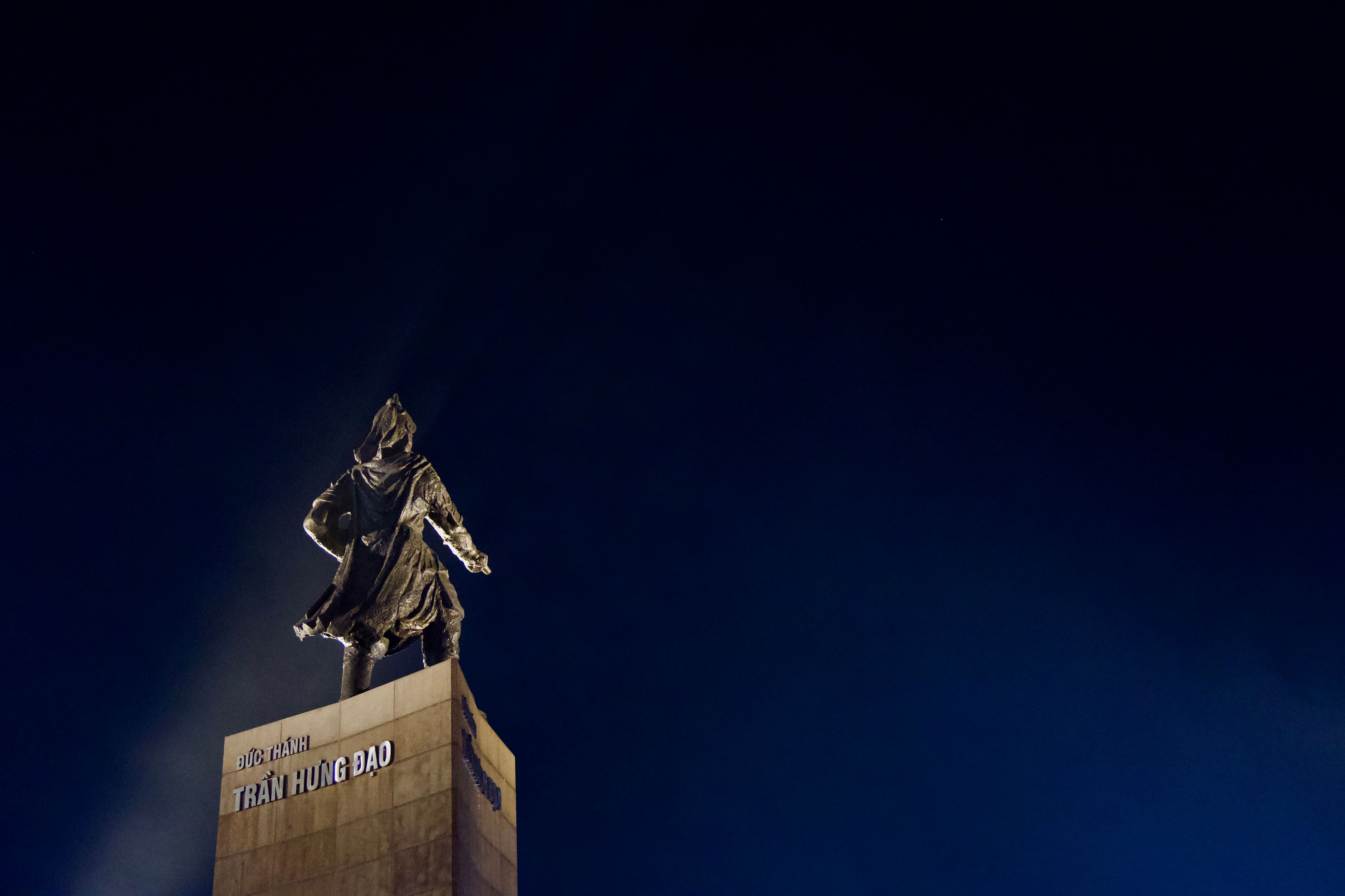Dramatic night view of the Tran Hung Dao statue against a deep blue sky in Vietnam.