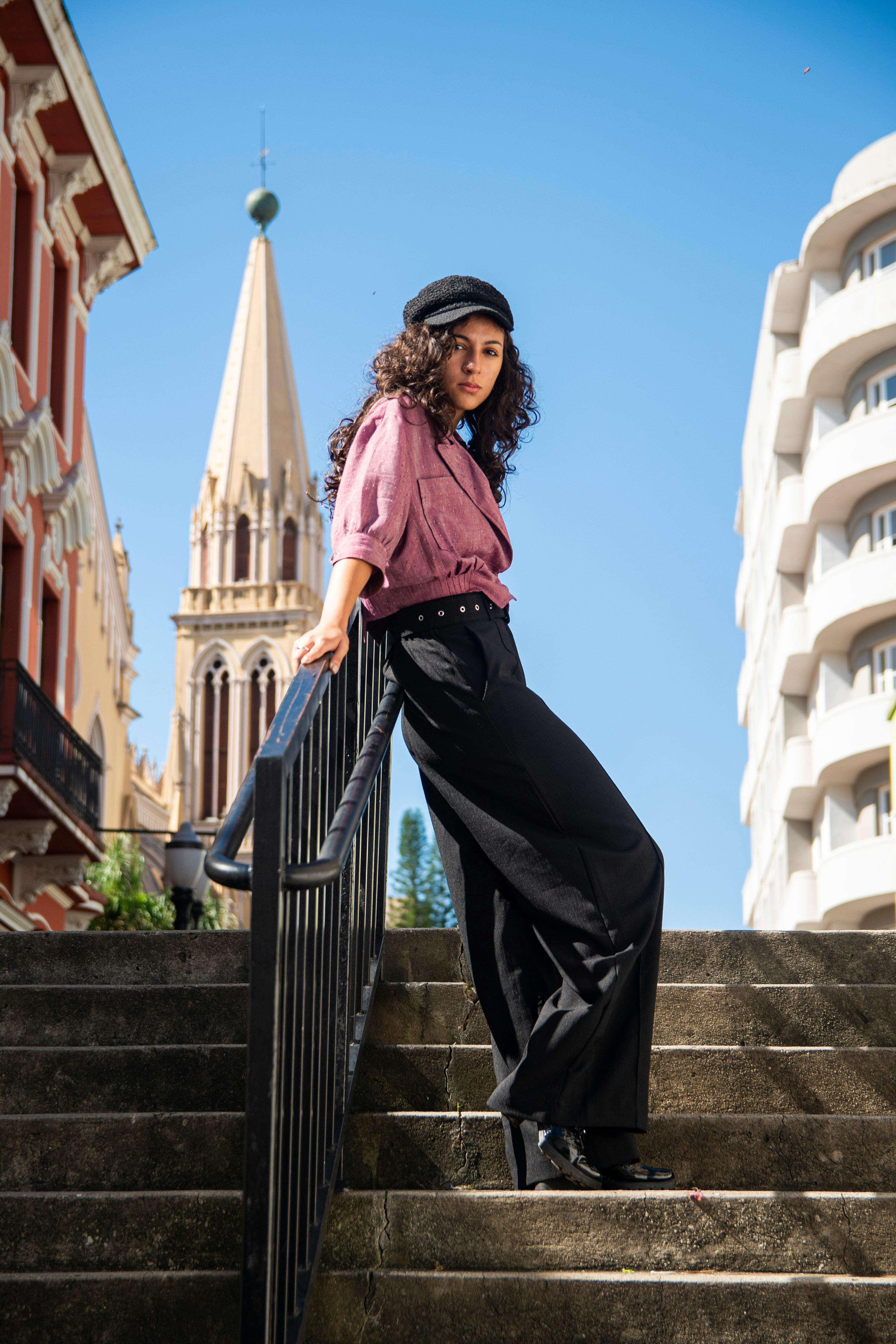 Stylish woman in urban setting with architectural background under clear blue sky.
