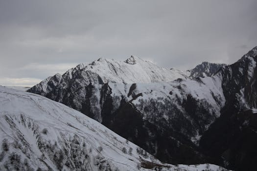 Breathtaking view of snow-covered mountains under cloudy skies, showcasing winter's beauty.