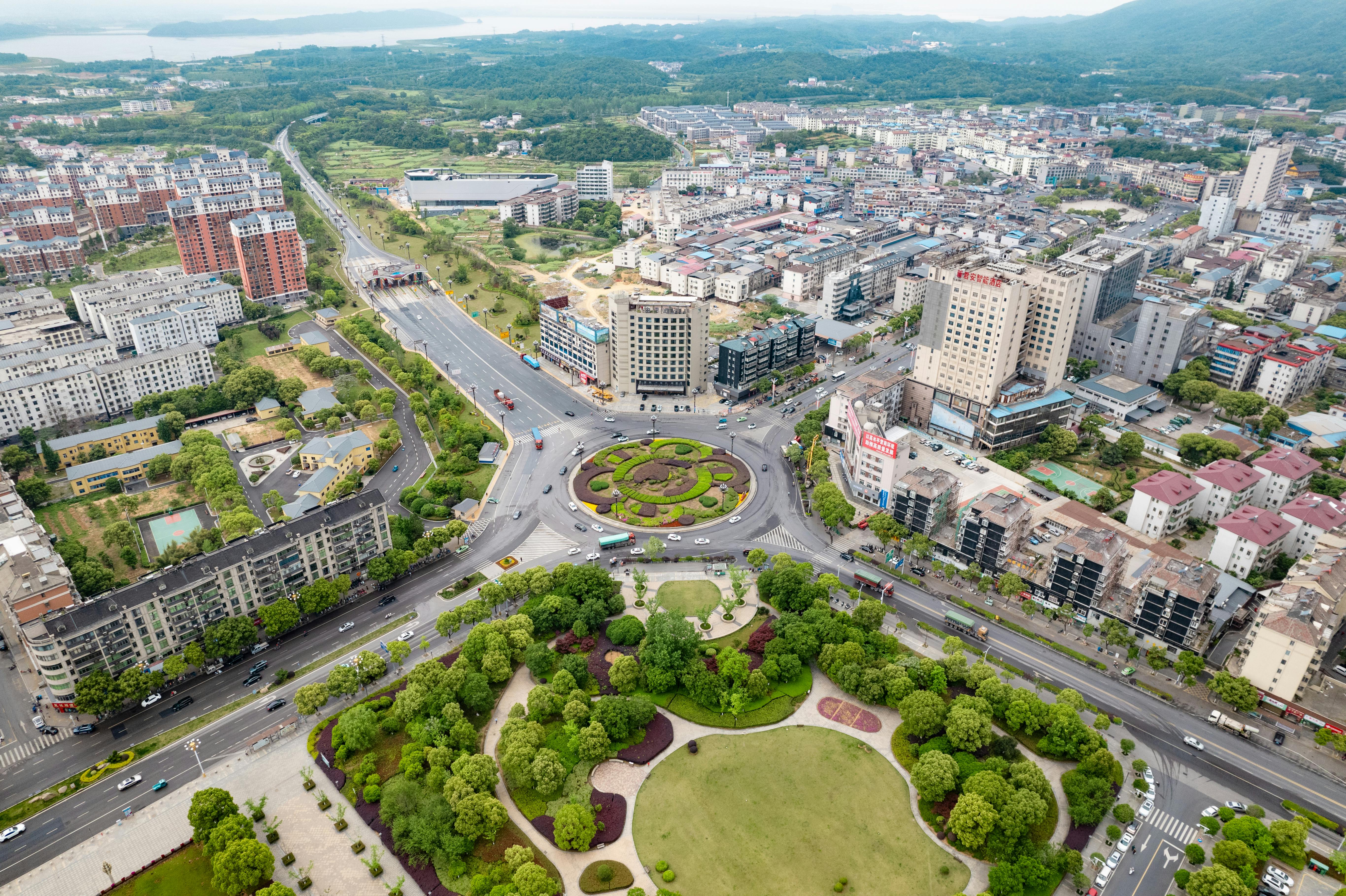 Stunning aerial shot of a bustling city with a prominent roundabout, showcasing urban planning and green spaces.