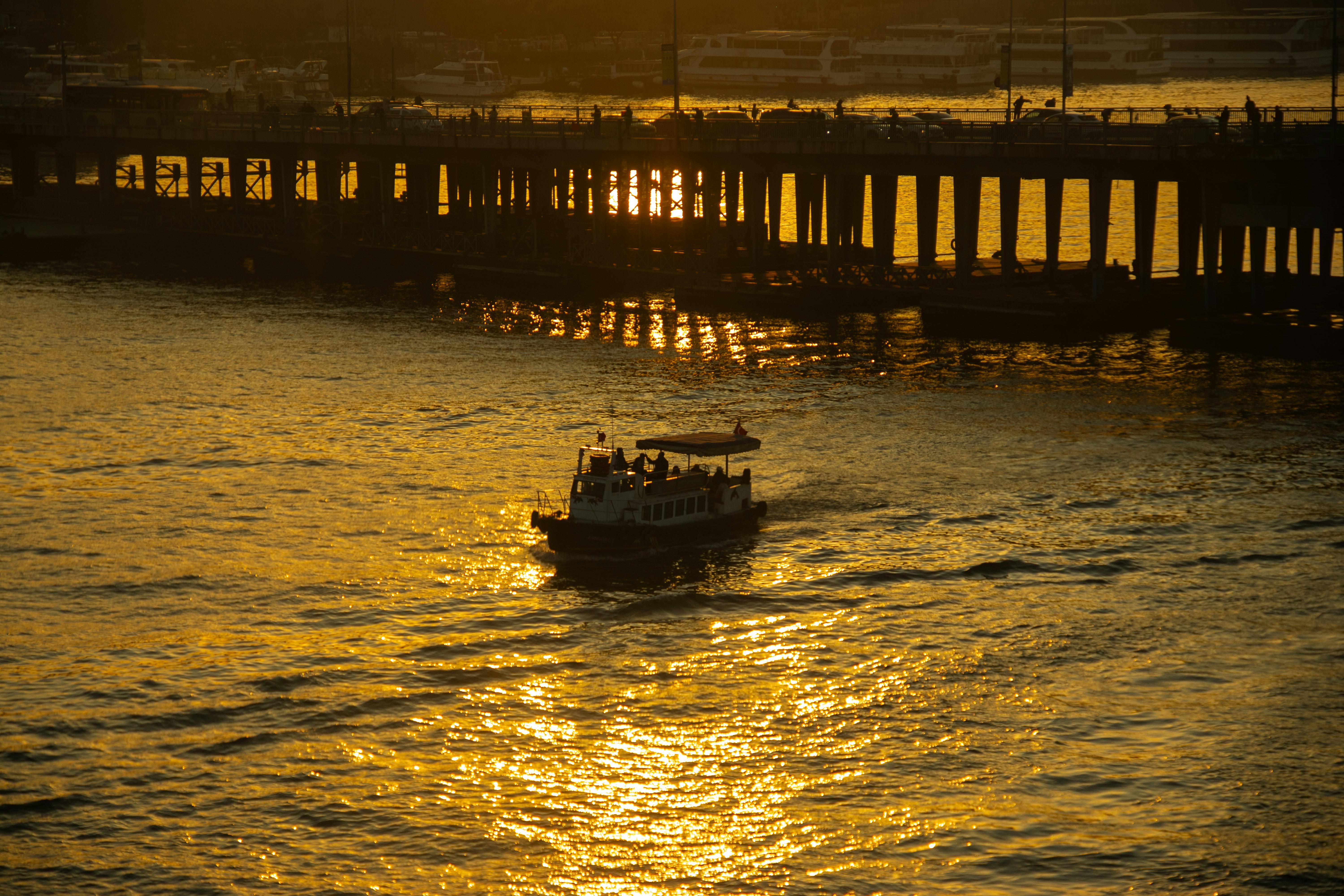 Gratuit Une vue panoramique du coucher de soleil sur la Corne d'Or d'Istanbul avec un bateau et la silhouette d'un pont. Photos