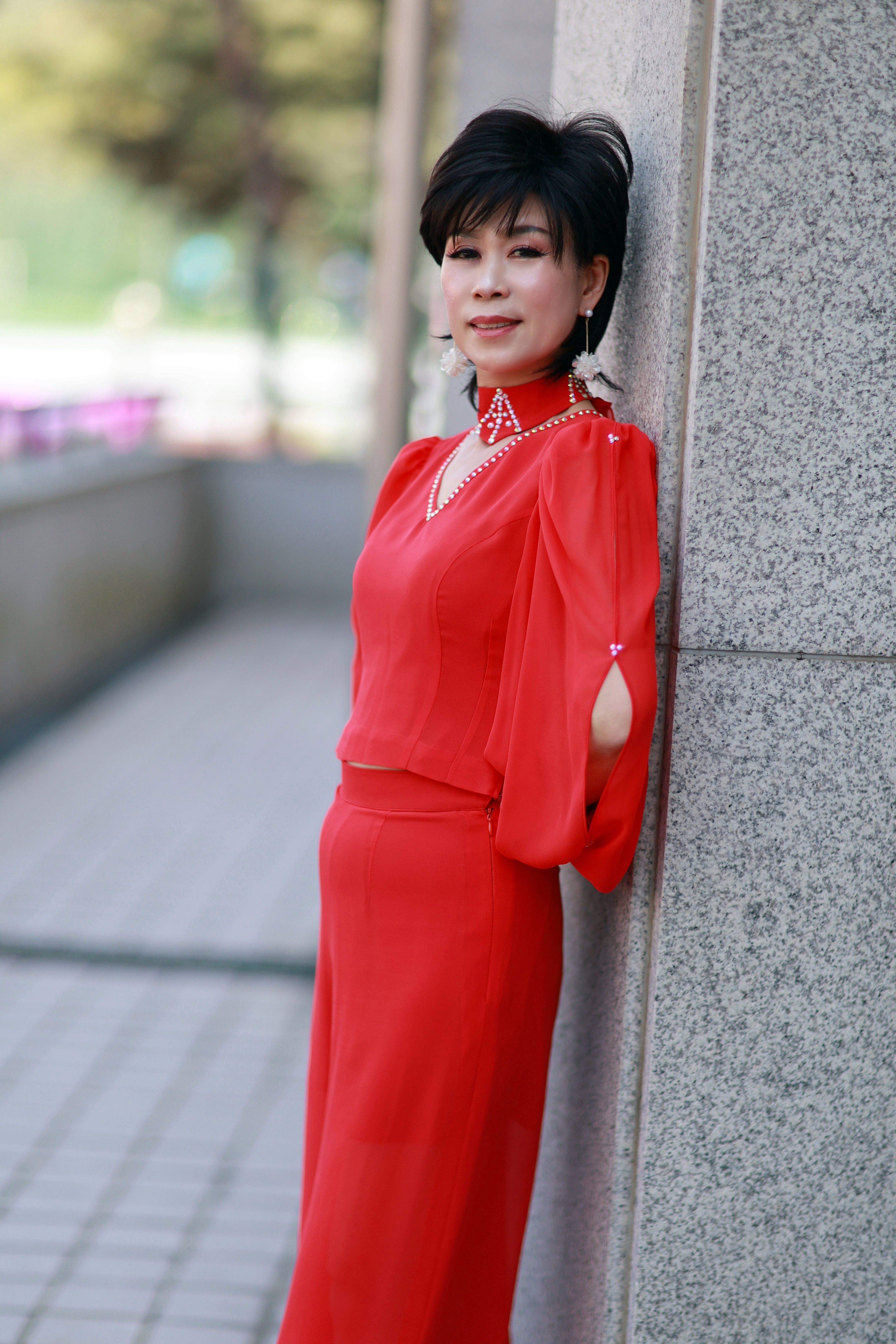 Elegant Woman in Red Dress Leaning Against Wall Outdoors · Free Stock Photo