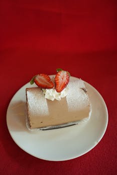 Tempting dessert log with strawberries and cream on a red background.