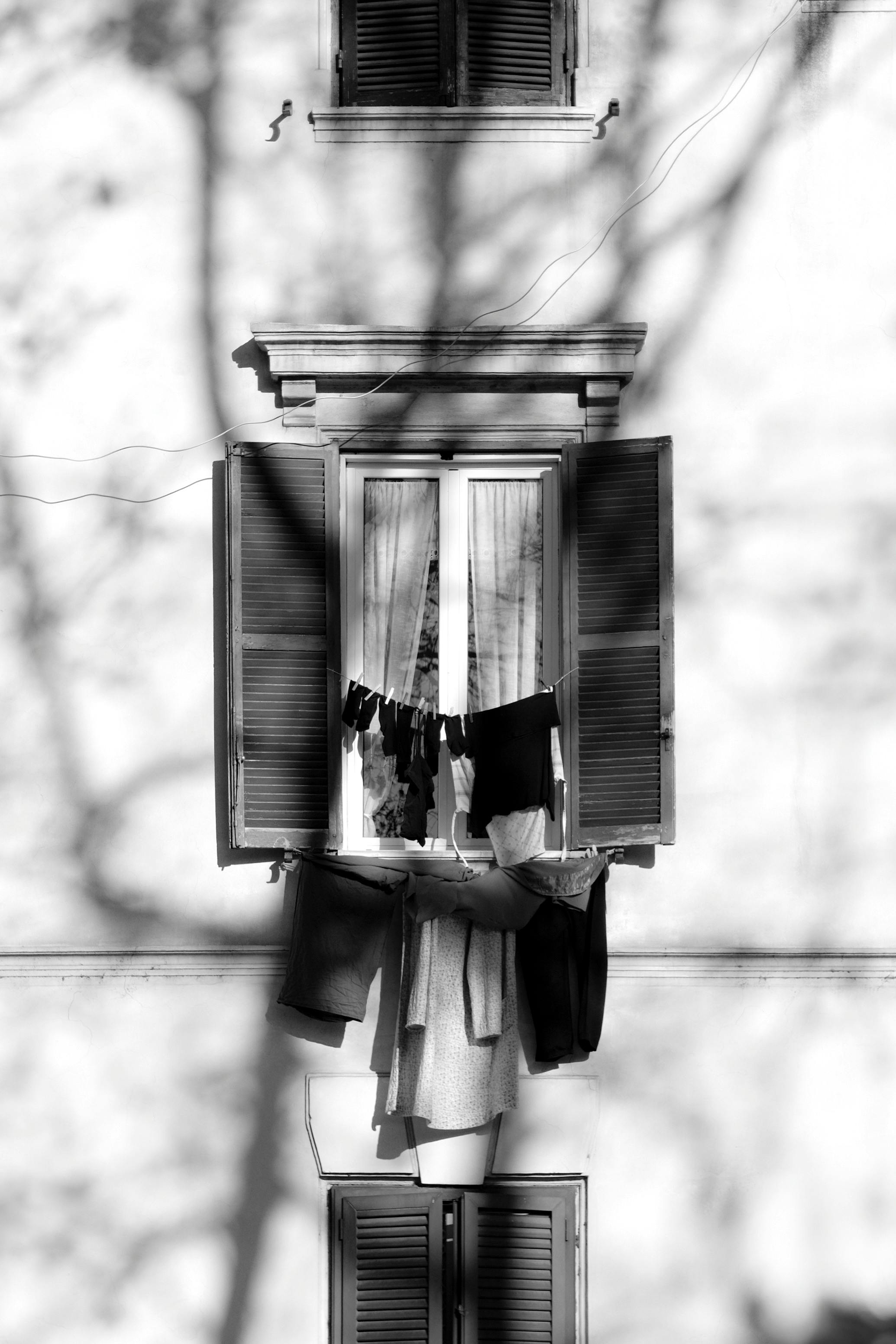 Free Monochrome window with drying clothes and tree shadows. Stock Photo