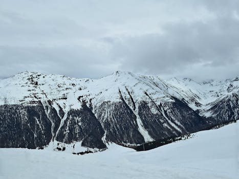 Scenic view of majestic snow-covered mountains under a cloudy sky.