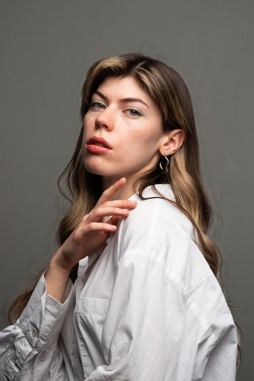 Free Striking portrait of a woman in a white shirt with long hair and earrings, looking contemplative. Stock Photo
