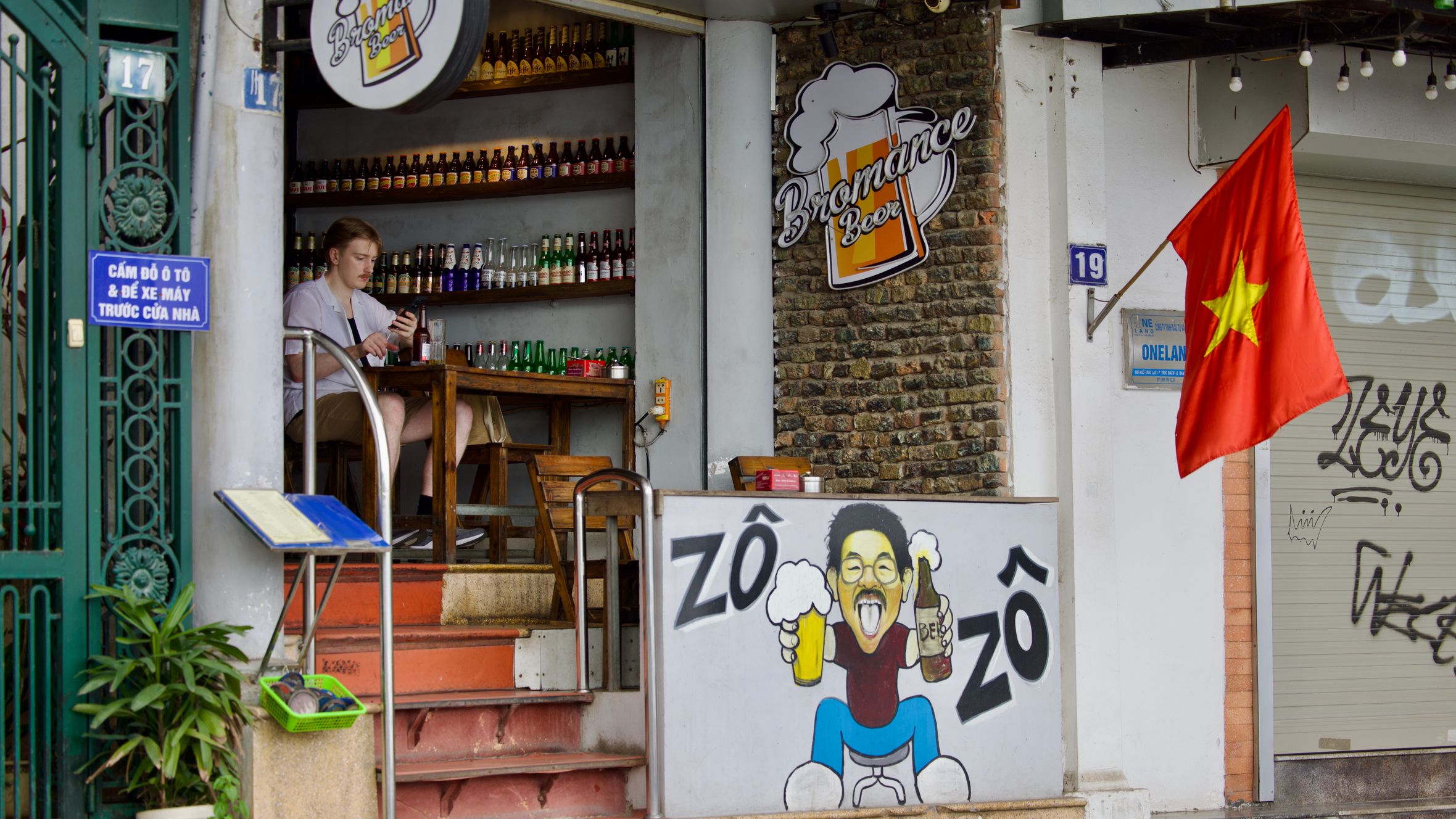 Cozy street bar in Vietnam with colorful bottles and Bromance Beer sign.