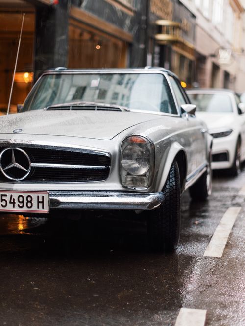 Free Vintage Mercedes car parked on a wet Vienna street on a rainy day, showcasing classic design and urban lifestyle. Stock Photo