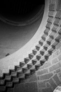 Black and white photo of a spiral stone staircase featuring geometric design in Pierrefonds, France.