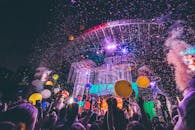 热闹的观众们享受着五彩纸屑和气球点缀的夜间音乐会，现场氛围充满活力，令人兴奋