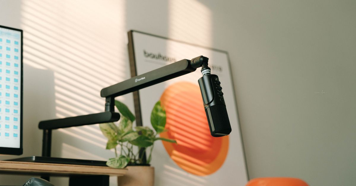 Stylish home office desk with microphone, plant, and modern decor in natural lighting.