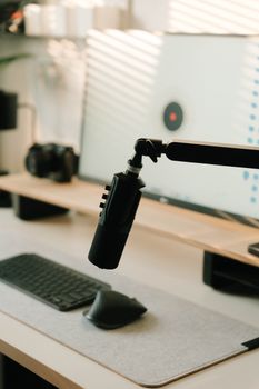 A sleek podcasting setup featuring a microphone, keyboard, and computer screen.